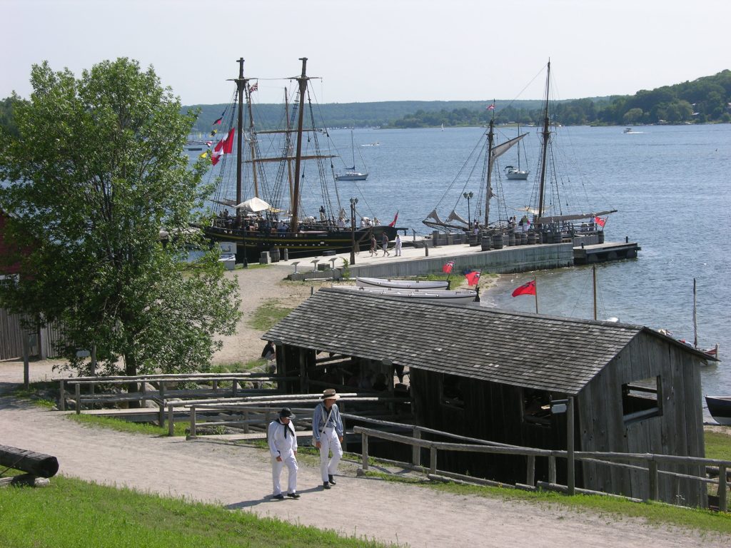 Deux interpr&egrave;tes historiques en costumes de marins qui marche le long de la route principale du site historique, avec les navires et la menuiserie historique dans l'arri&egrave;re plan