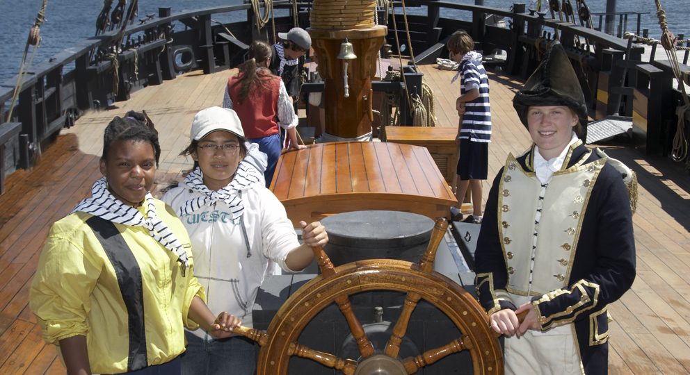 Plusieurs interprètes historiques en costumes à parler avec des visiteurs sur le pont d'un navire