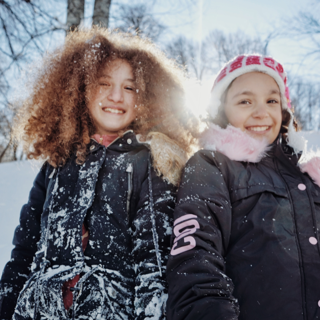 two girls looking happy to be outside on a bright, snowy day