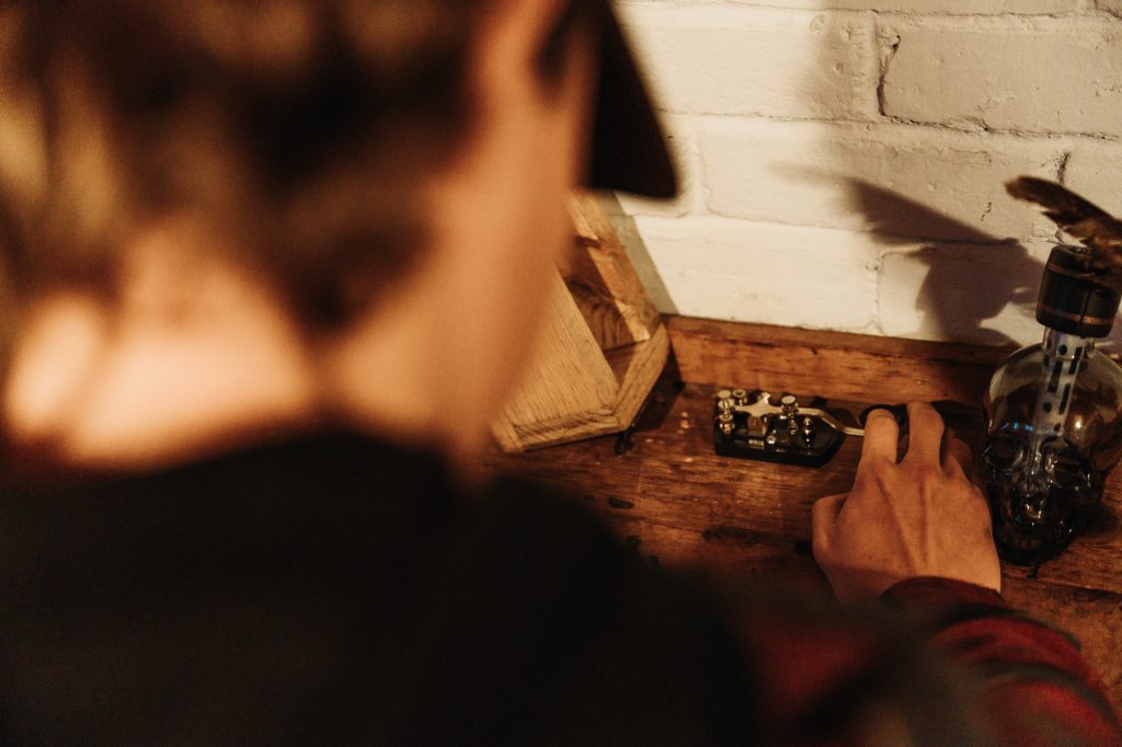 A guest taking a close look at a morse code machine as part of the escape room