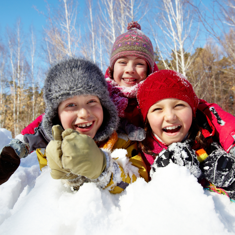 kids smiling in a pile of snow